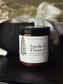 Jar of 'Smoked Flannel' candle by Hallowed Roots on a dark surface with blurred background